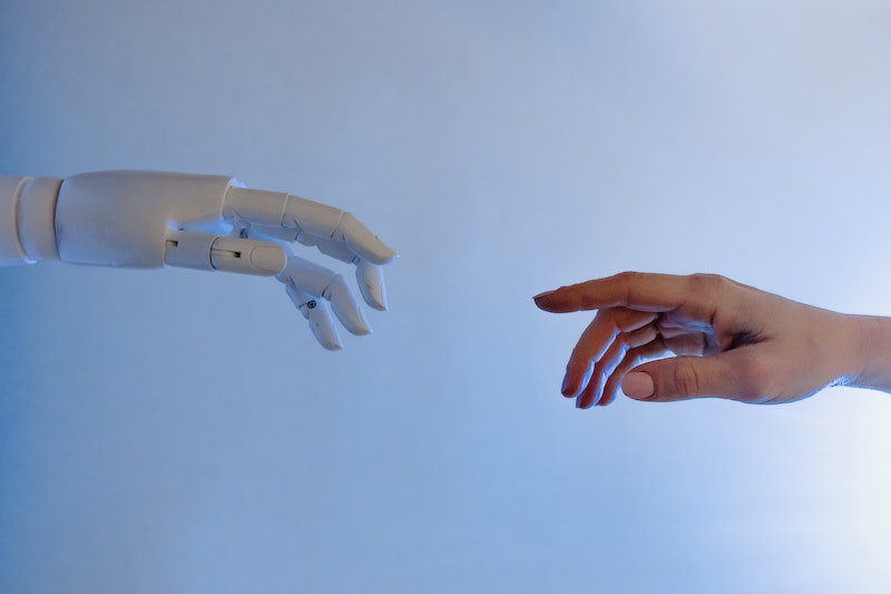 an image of an ai robot hand touching a human hand to illustrate how artificial intelligence is being used in the recruiting process