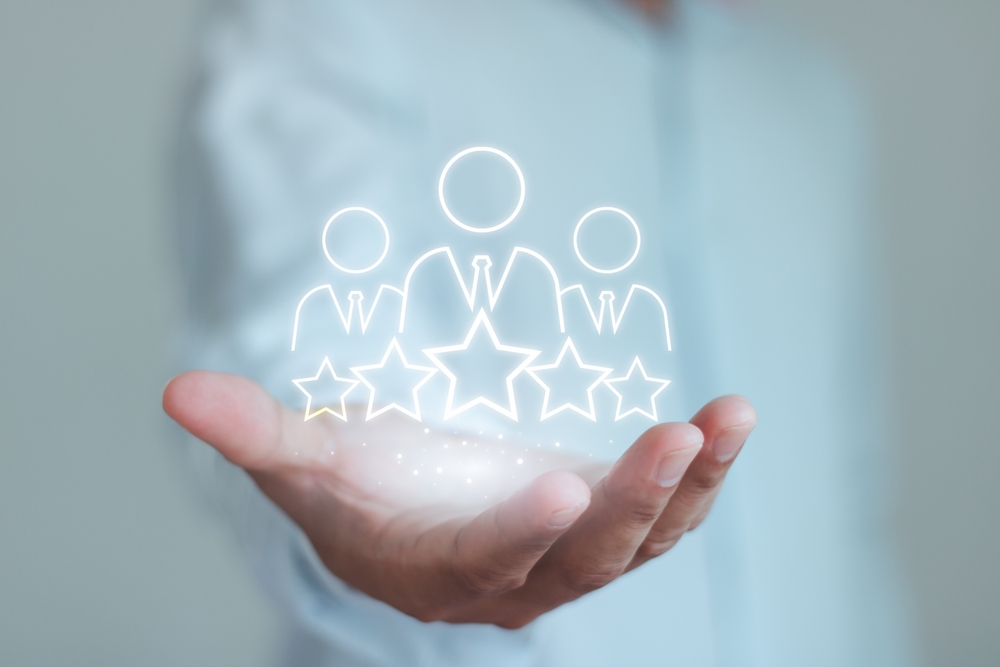 a man's hand outstretched with a holographic image of three people figures with star ratings below